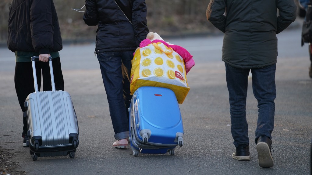 Ukrainische Flüchtlinge verlassen mit einem Rollkoffer ein Ankunftszentrum.
