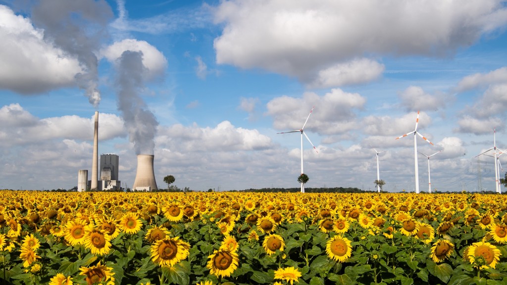 Ein Sonnenblumenfeld mit einem rauchenden Kraftwerk und Windrädern