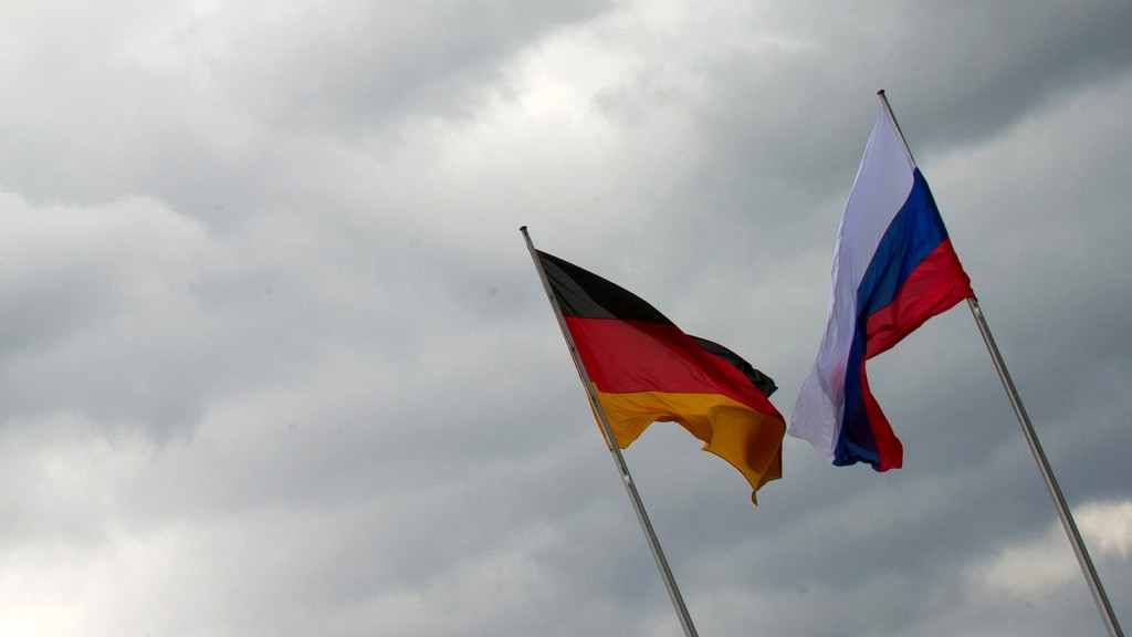 Die russische und die deutsche Flagge wehen vor einem grauen Himmel