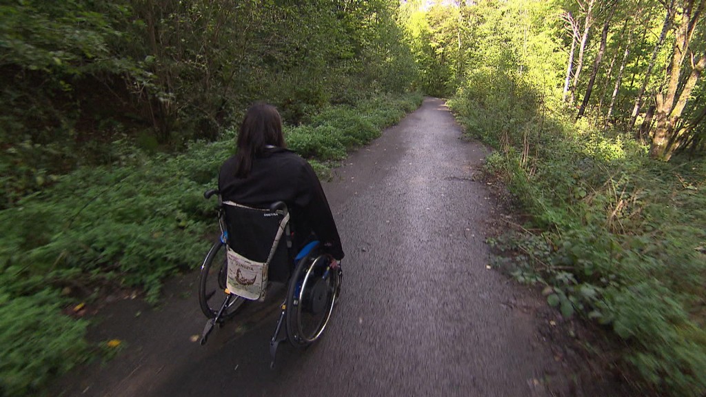 Foto: Rollstuhlfahrerin auf einem Waldweg