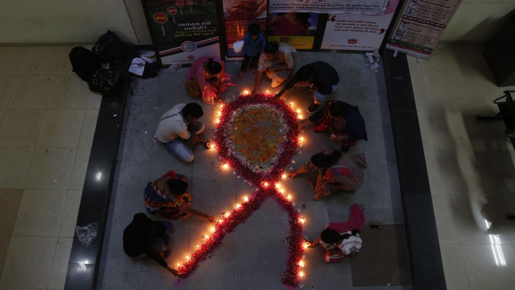 Mitglieder einer Nichtregierungsorganisation formen mit Kerzen eine rote Schleife