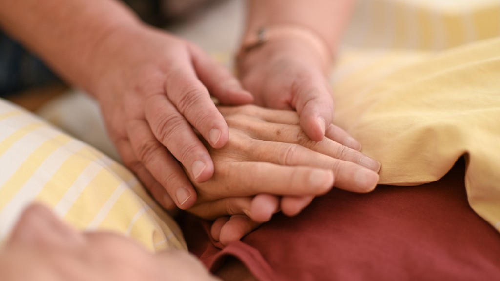 Eine Hospizmitarbeiterin hält die Hand eines todkranken Menschen