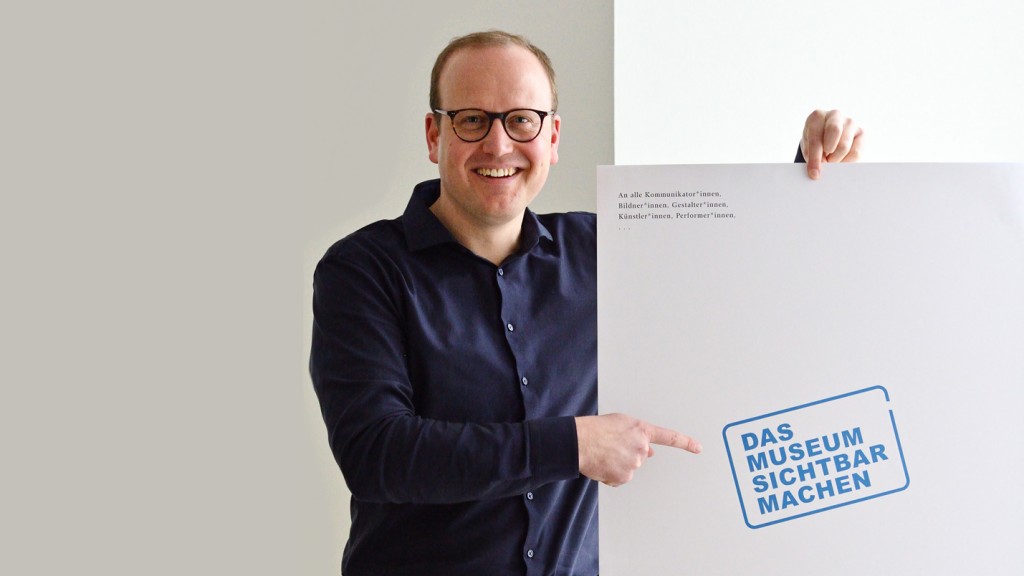 Simon Matzerath mit Plakat zum Ideenwettbewerb „Das Museum sichtbar machen“