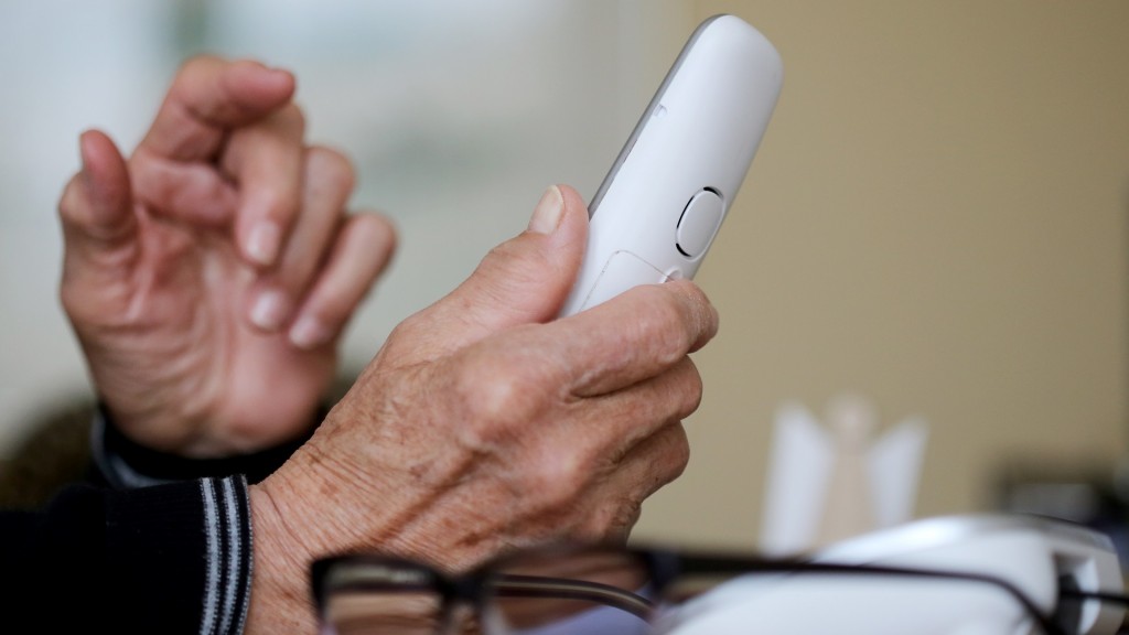 Eine ältere Person hält einen Telefonhörer in der Hand.