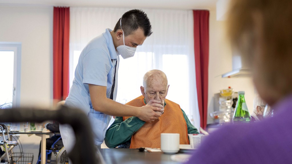 Symbolbild: Ein Pfleger hilft einem Mann zu trinken