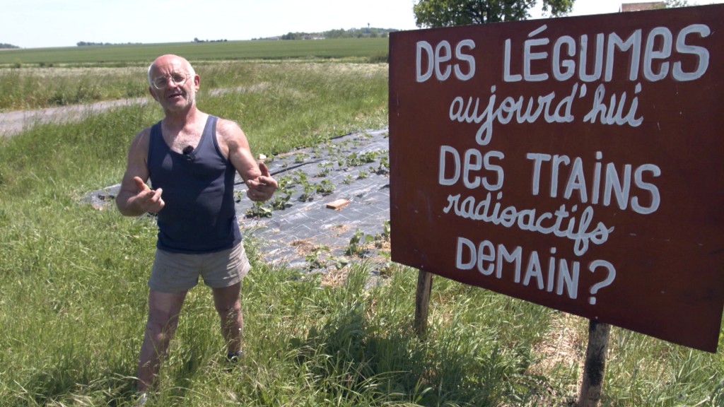 Foto: Ein Mann steht neben einem Schild, auf dem auf Französisch steht: 