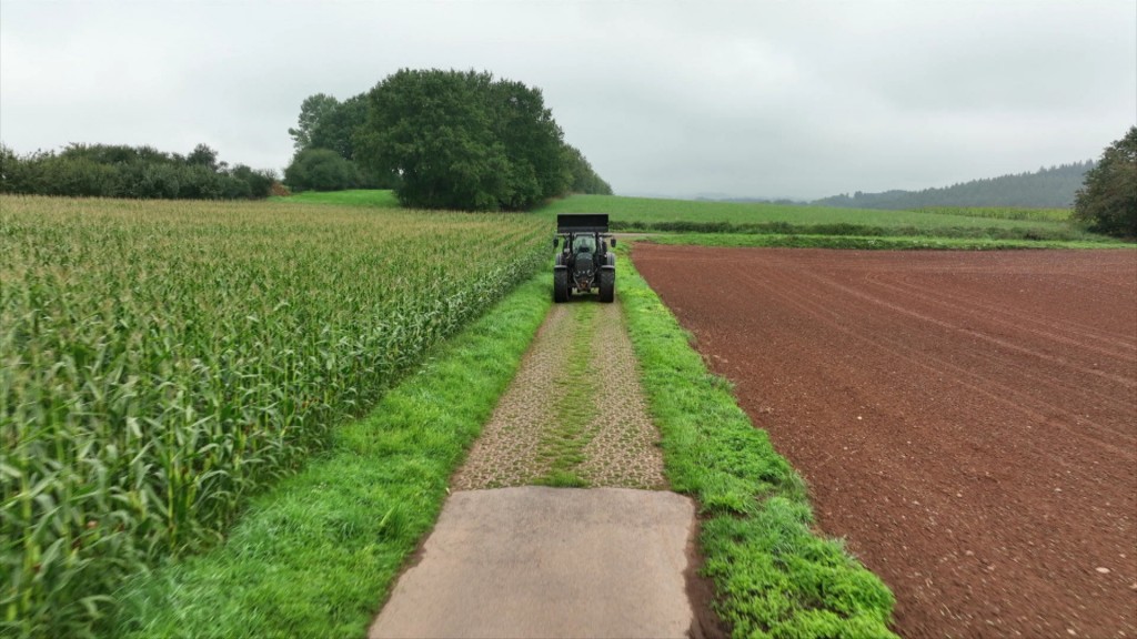 Foto: Ein Traktor auf einem landwirtschaftlichen Weg zwischen zwei Feldern