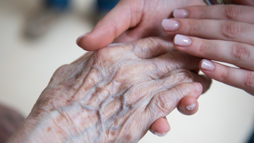Bild: Eine Pflegerin hält im Seniorenzentrum die Hand einer Bewohnerin