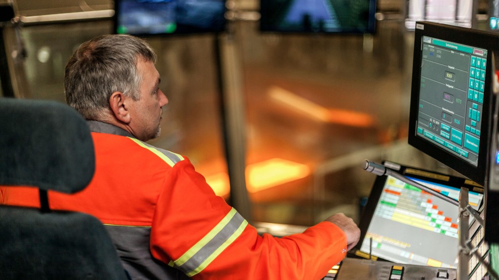 Steuerstand im Walzwerk, ein Techniker überwacht die Stahlproduktion auf Bildschirmen