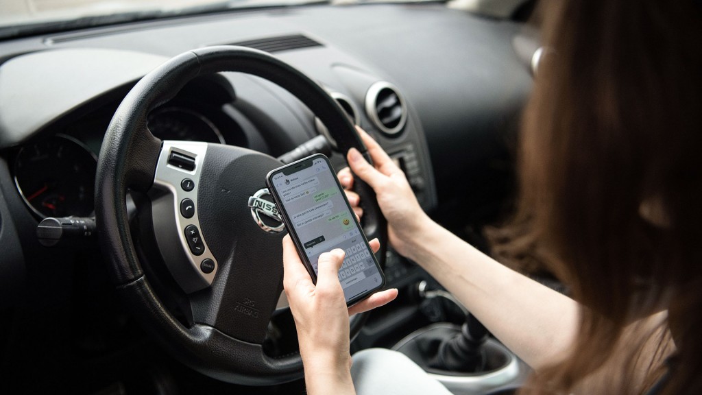 Foto: Gestellte Szene: Eine Frau schreibt am Smartphone beim Autofahren