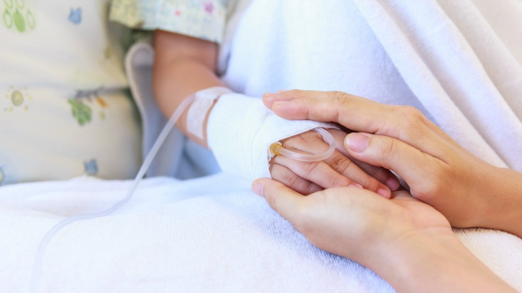 foto: Eine Mutter hält ihrem Kind am Krankenbett die Hand