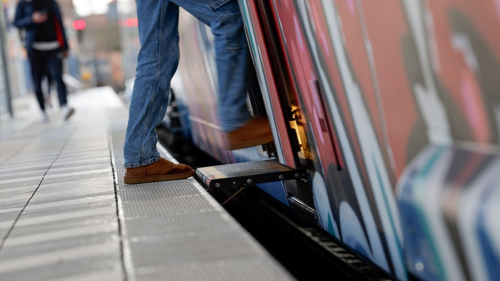 Eine Person steigt in einen Zug am barrierefreien Bahnsteig
