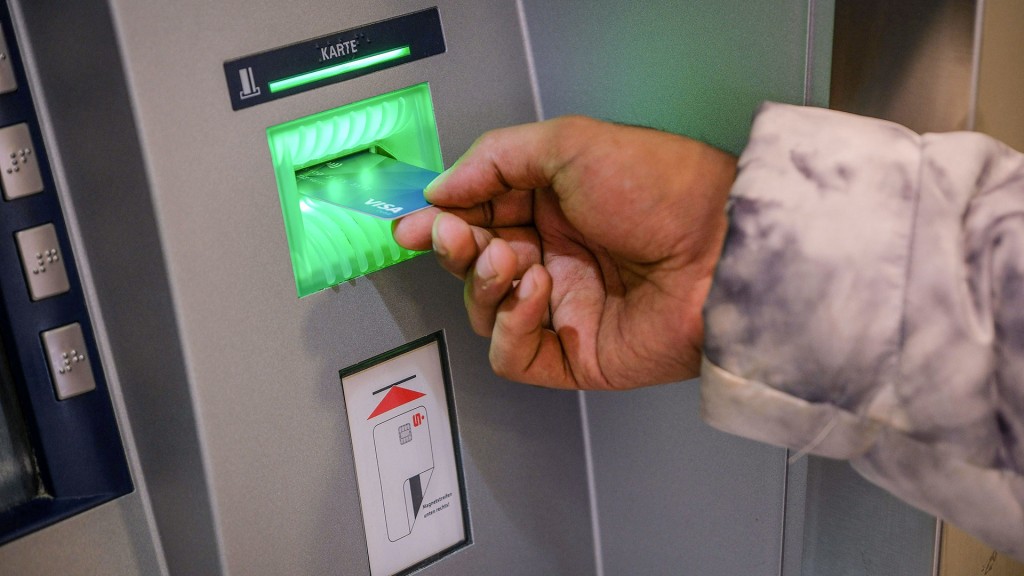 Eine Hand mit einer Bankkarte vor einem Geldautomaten