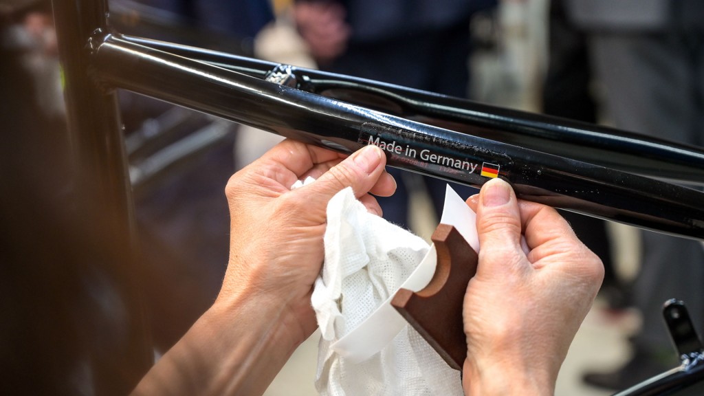 Der Aufkleber „Made in Germany“ wird von einer Mitarbeiterin an einen Fahrradrahmen geklebt