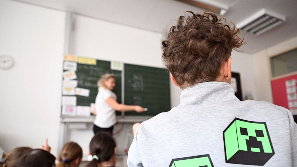 Eine Lehrerin steht vor einer Klasse an der Tafel