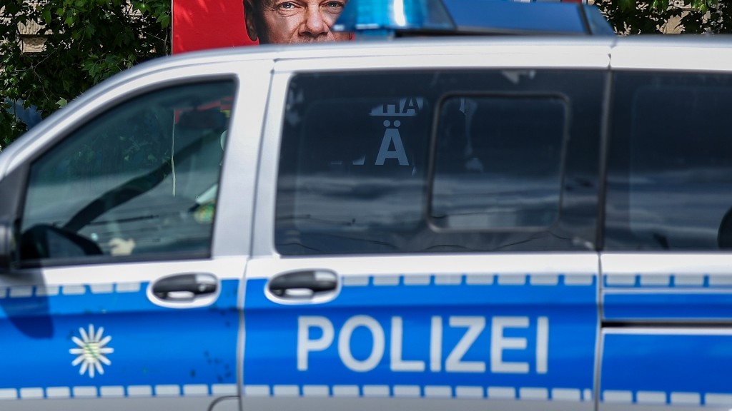Ein Streifenwagen der Polizei vor einem Wahlplakat der SPD mit dem Foto von Bundeskanzler Scholz.