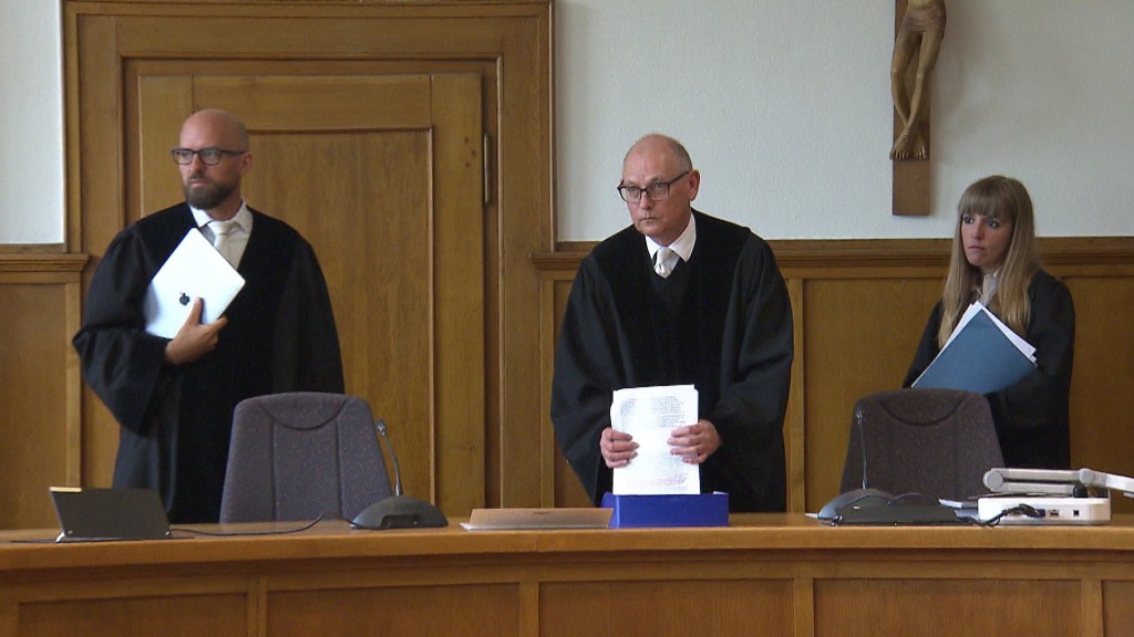 Foto: Drei Menschen hinter Richterpult