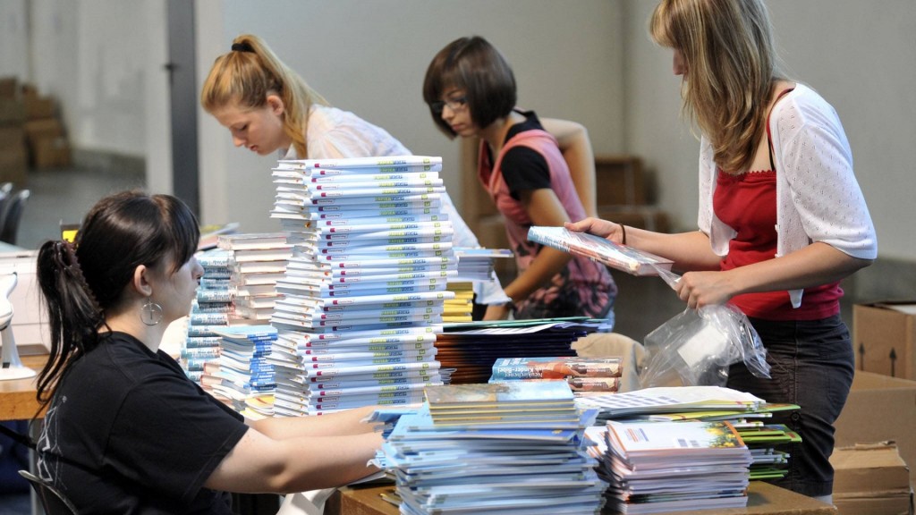Eine Schülergruppe hilft Schulbücher für die Schulbuchausleihe zu packen.