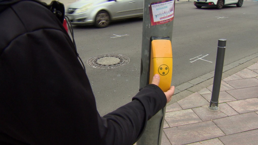 Foto: Ein blinder Mann am Schalter einer Fußgänger-Ampel