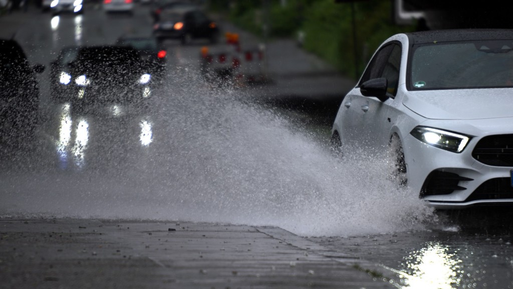 Symbolbild: Ein Auto fährt durch eine große Wasserlache.