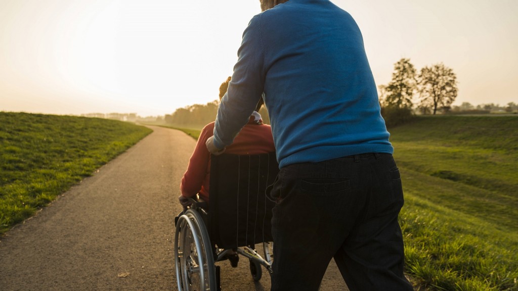 Ein älterer Mann schiebt eine Seniorin im Rollstuhl
