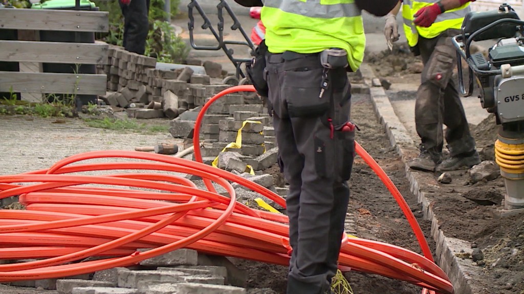 Foto: Zwei Bauarbeiter verlegen Glasfaserkabel im Boden