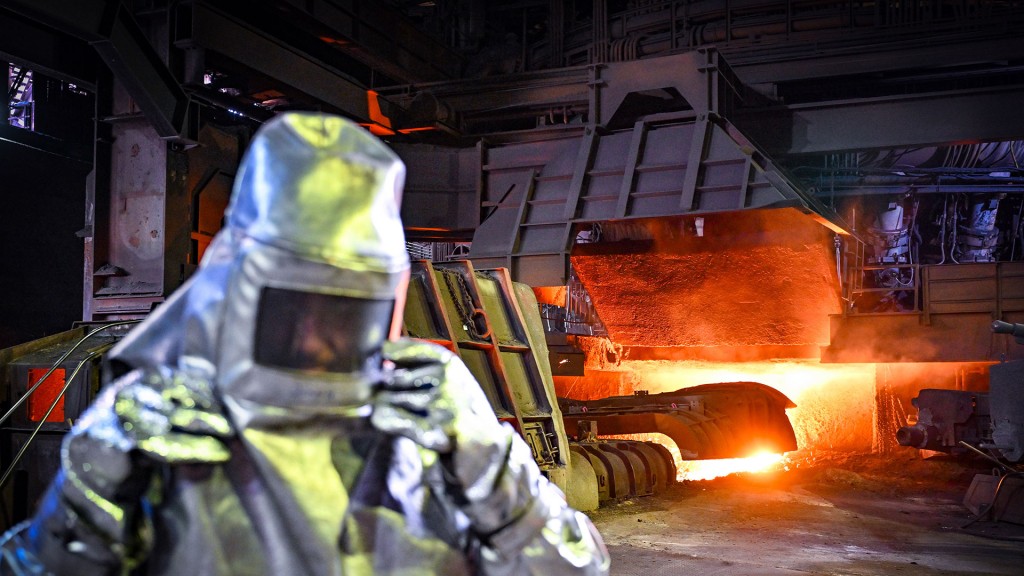 Ein Stahl-Arbeiter zieht den Helm seines Hitzesschutzanzuges aus