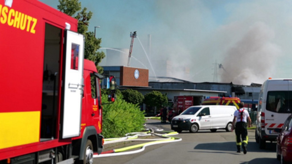 Foto: Feuerwehrmann läuft auf brennende Lagerhalle zu 