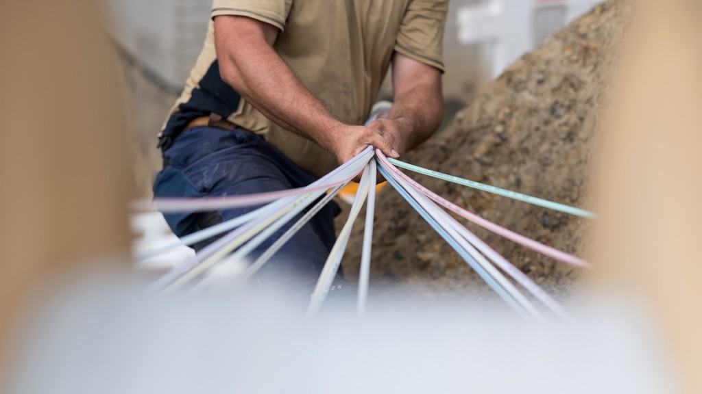 Foto: Ein Mitarbeiter einer Firma bündelt Glasfaser-Leerrohre auf einer Baustelle.