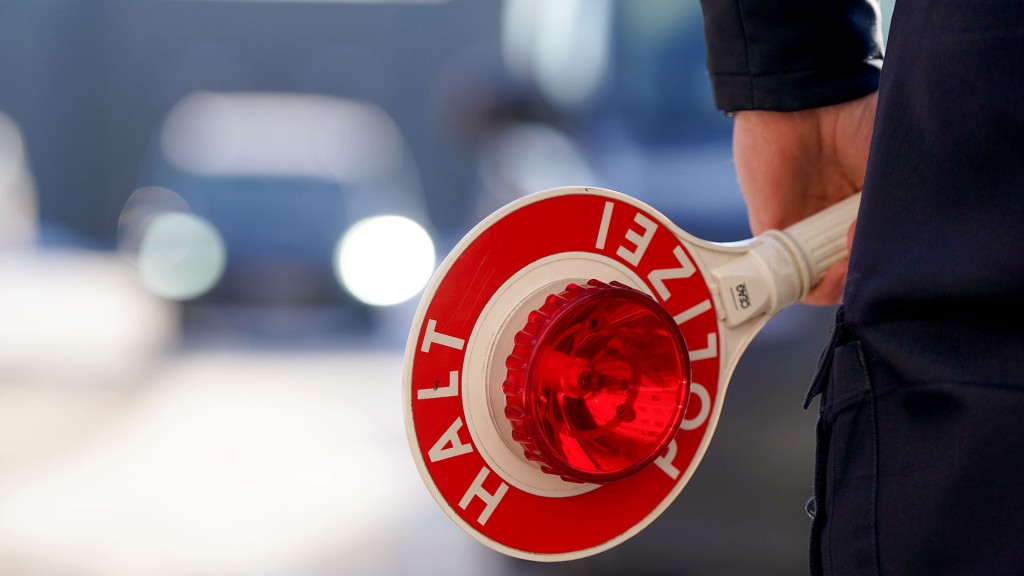 Foto: Ein Polizist hält eine Anhaltekelle in der Hand