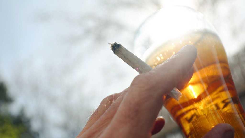 Eine Hand hält einen Joint neben einem Bierglas