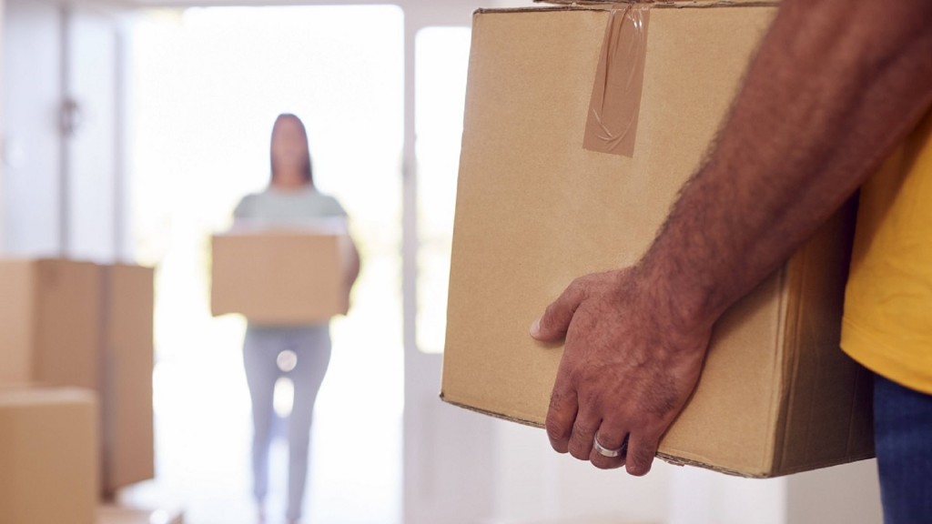 Zwei Personen tragen Umzugskisten in eine Wohnung.