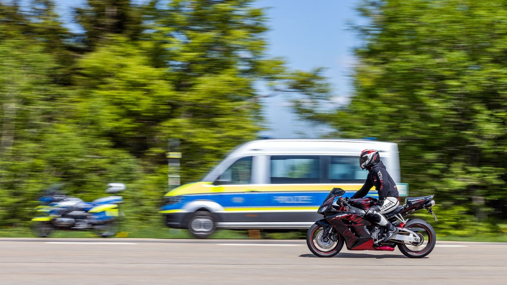 Foto: Ein Motorrad fährt an Einsatzfahrzeugen der Polizei vorbei