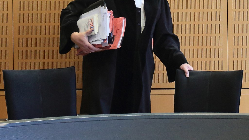 Foto: Ein Richter rückt sich in einem Verhandlungssaal seinen Stuhl zurecht.