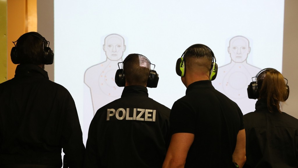 Foto: Polizisten stehen auf einem Schießstand vor einer Wand mit projizierten Zielen.