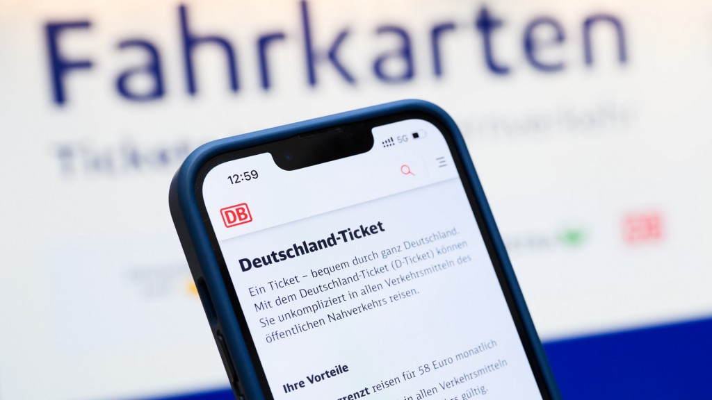 Eine Person hält am Hauptbahnhof ein Smartphone in der Hand, auf dessen Display eine Information zum Kauf des Deutschlandtickets zu sehen ist