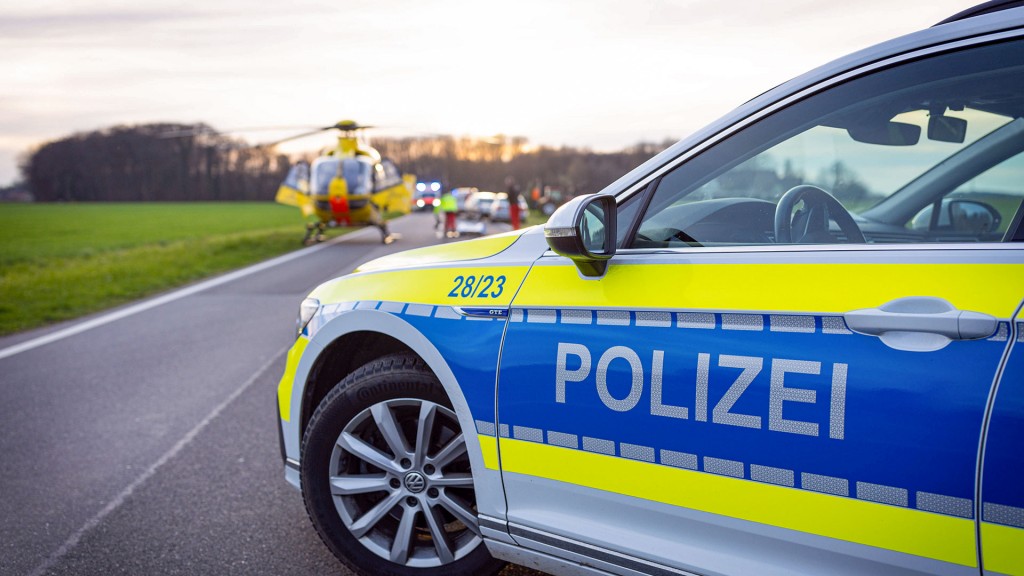 Ein Einsatzfahrzeug der Polizei bei einem Verkehrsunfall auf einer Landstraße. Rettungsdienst und Hubschrauber im Hintergrund