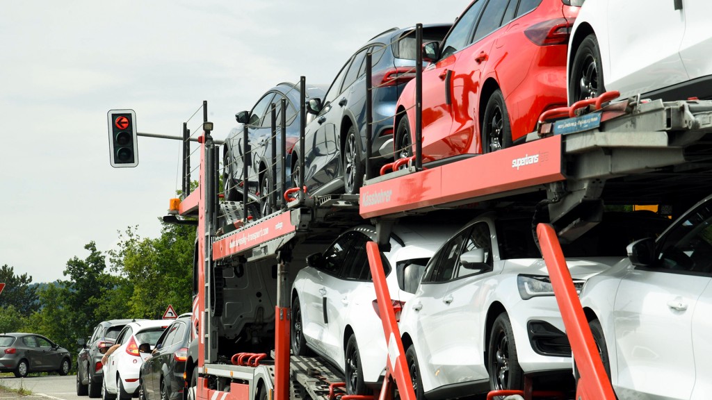 Foto: Ein Auto-Transporter steht mit neuen Fahrzeugen an einer roten Ampel vor dem Ford-Werksgelände in Saarlouis