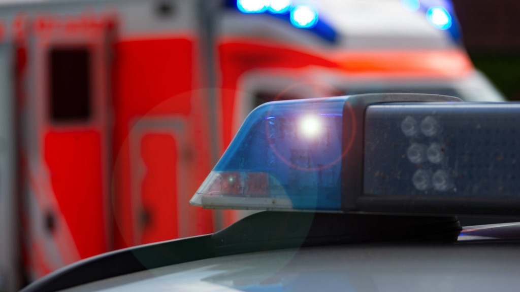 Foto: Einsatzfahrzeug, Streifenwagen der Polizei mit Blaulicht, im Hintergrund sieht man einen Rettungswagen