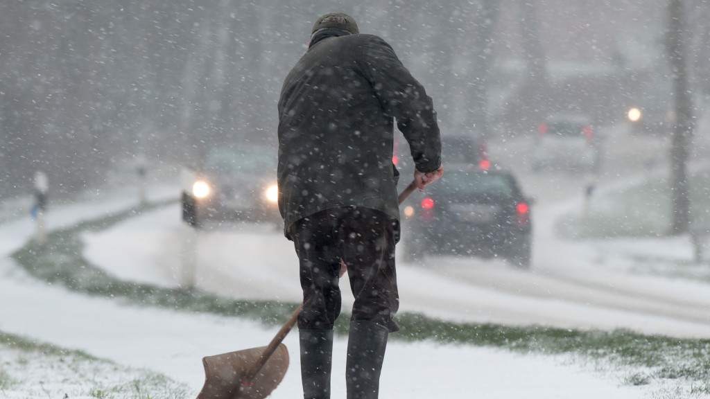 Ein Mann räumt den frisch gefallenen Schnee