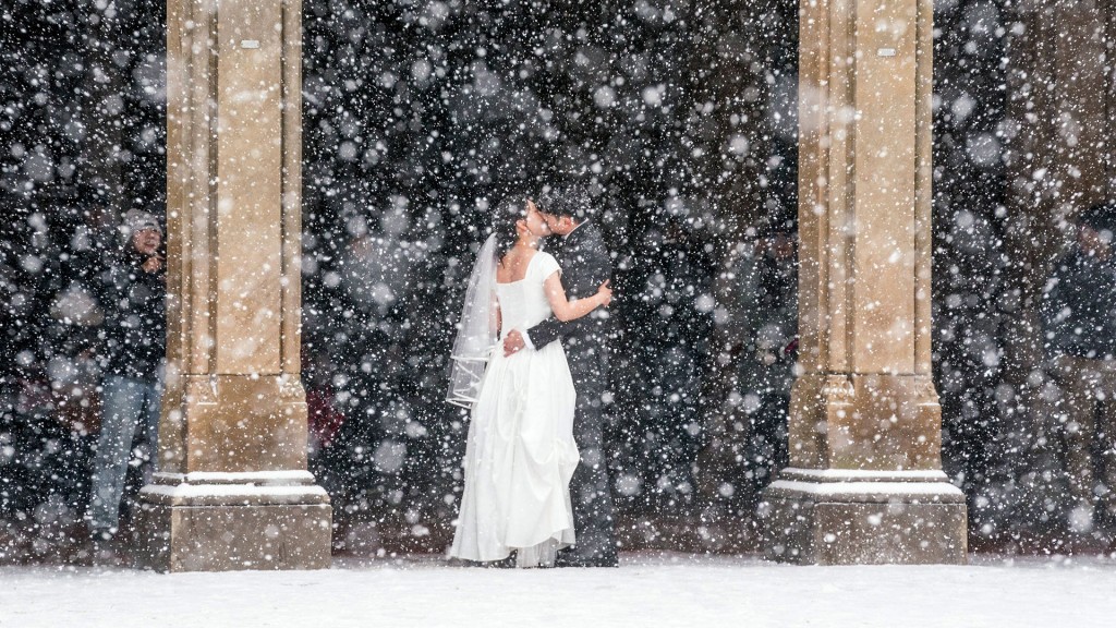 Ein Hochzeitspaar küsst sich in starkem Schneefall
