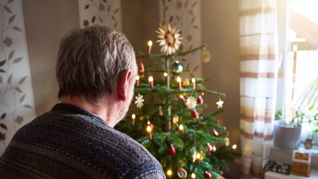 Foto: Mann betrachtet Weihnachtsbaum.