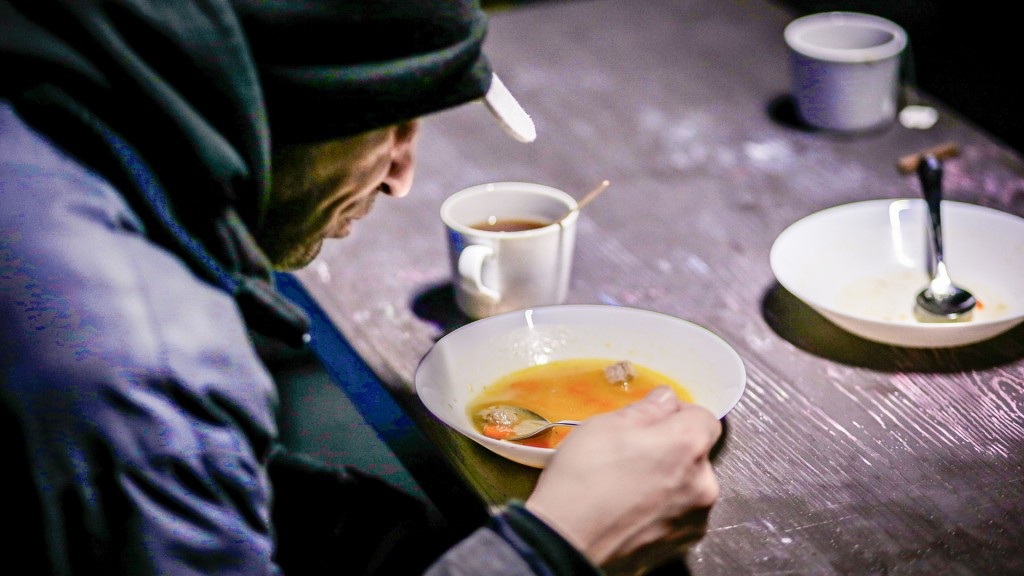 Ein Obdachloser sitzt in einer Kältehilfe-Einrichtung beim Essen