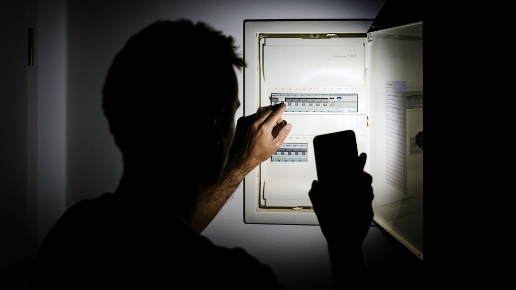 Jemand leuchtet mit der Handytaschenlampe bei Dunkelheit in den Stromkasten