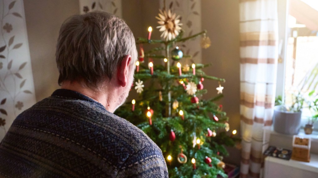 Mann steht vor seinem Weihnachtbaum