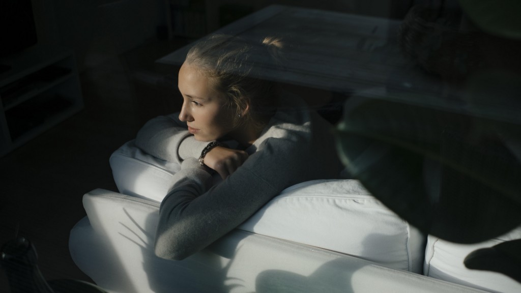 Eine junge Frau liegt auf dem Sofaund schaut zum Fenster