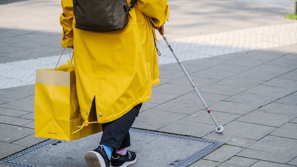 Foto: Eine Sehbehinderte Person geht mit einem blindenstock auf die Straße