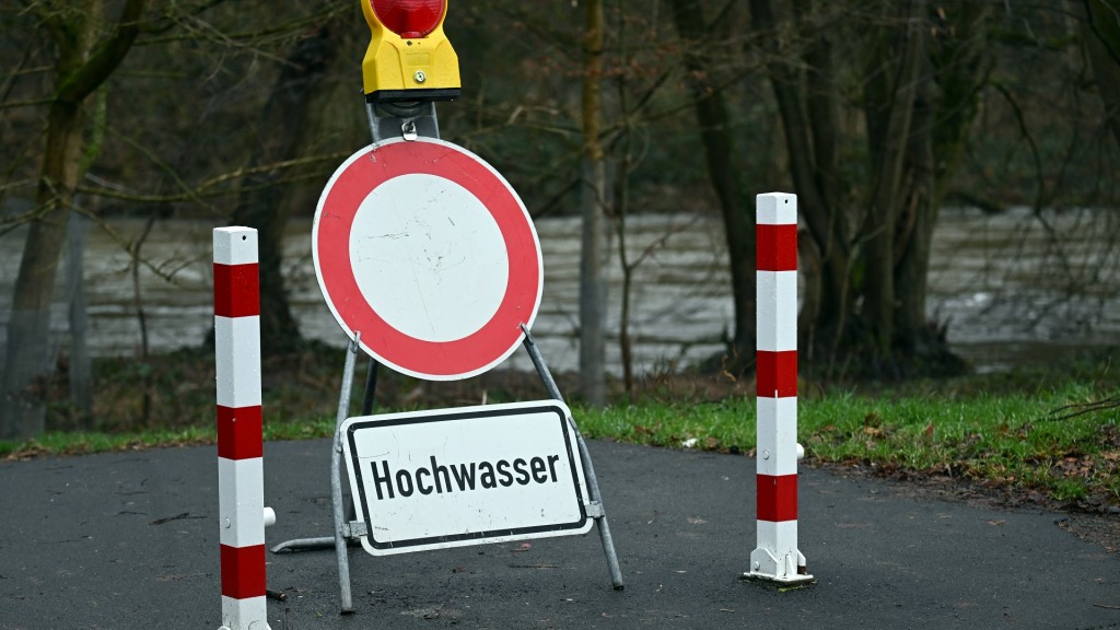 Ein Schild warnt an einem gesperrten Weg vor dem Hochwasser.