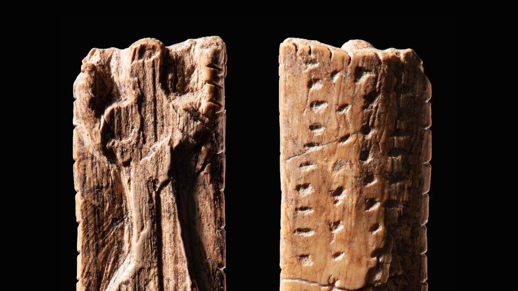 Eine Elfenbeinplatte mit einer anthropomorphen Figur und mehreren Reihen von Kerben und Punkten.