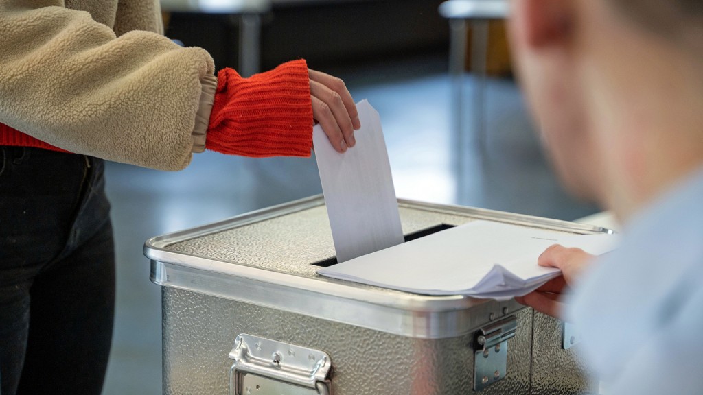 Foto: Eine Frau steckt ihren Stimmzettel in eine Wahlurne